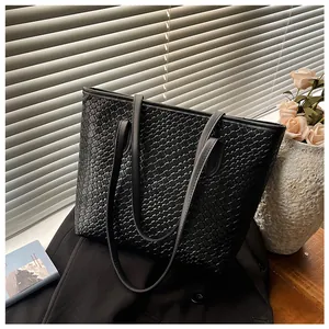 Close-up of black woven leather tote bag with fine cross-texture detail on suit
