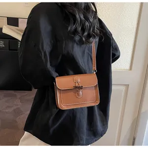 Close-up of brown leather crossbody bag featuring white stitching and a horn buckle detail