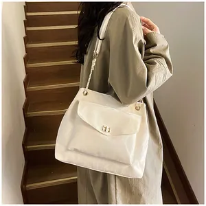 Détail d'un sac cabas en cuir beige avec fermoir doré et bandoulière chaîne sur modèle