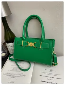Detailed view of green handbag with gold heart-shaped buckle on an elegant French vintage desk