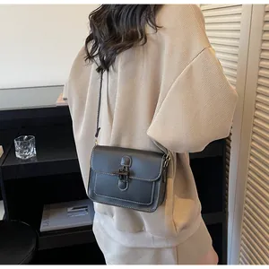 Detail of black crossbody bag with white stitching and distinctive horn buckle on a model