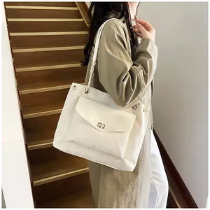Détail du sac cabas crème avec poche avant, boucle métallique et bandoulière chaîne