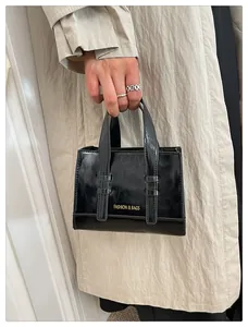 Detail of glossy black mini tote bag featuring white Fashion & Bags printed text