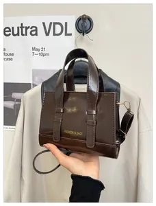 Detail of dark brown glossy leather handbag with gold hardware and embossed lettering