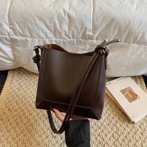 Detail view of brown matte leather tote with knotted shoulder strap and gold hardware