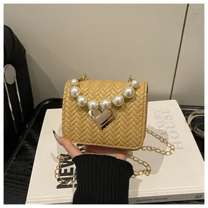 Detail of khaki woven square bag featuring pearl handle and silver heart lock