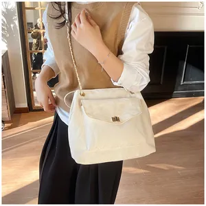 Détail d'un sac à bandoulière matelassé beige avec chaîne dorée et fermoir rotatif