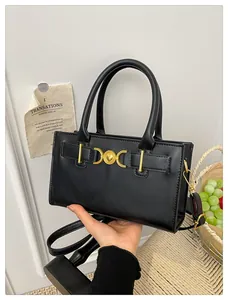 Detail of elegant black tote bag featuring heart-shaped gold hardware and chic top handles