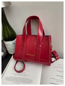 Glossy red leather handbag with fashion lettering and gold metal strap hardware