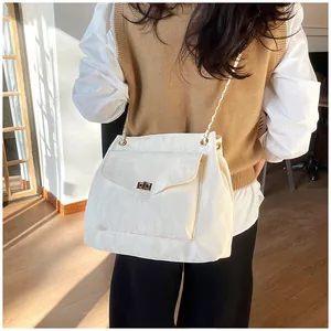 Détail du sac blanc crème à texture froissée avec chaîne dorée porté par un mannequin