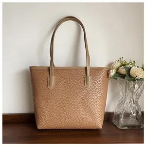 Close-up of woven texture on khaki tote bag with slender straps on a wood surface