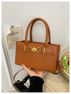 Detailed view of caramel brown leather handbag with gold heart ring metal buckle