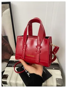 Macro detail of red glossy PU leather tote bag with gold lettering and handles