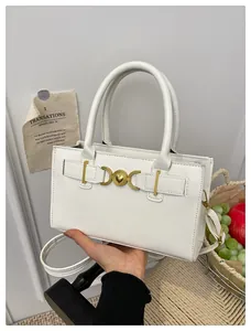 Close-up of elegant white leather handbag with golden heart-shaped lock and twin handles