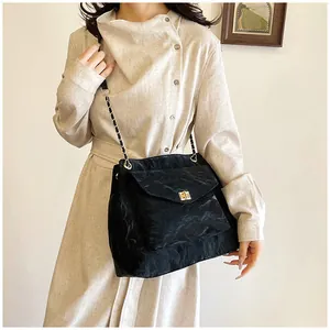 Gros plan d'un sac à bandoulière plissé noir avec chaîne dorée et fermoir en métal doré