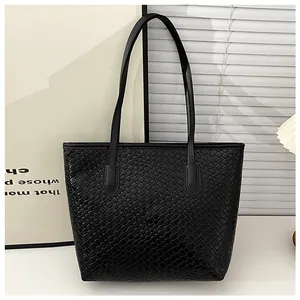 Detailed close-up of the black woven texture and leather strap on a minimalist tote bag