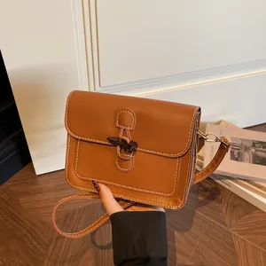 Detail of vintage brown square bag with white stitching and stylish horn buckle toggle