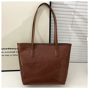 Macro shot of dark brown tote bag showing textured square grid pattern and handle detail