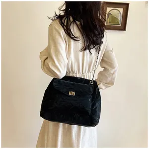 Détail du sac bandoulière noir brillant avec fermoir doré et bandoulière chaîne