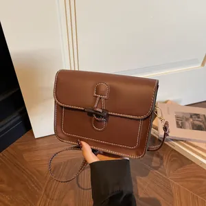 Detail of vintage brown leather bag with white contrast stitching and unique toggle closure