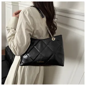 Gros plan d'un sac cabas noir matelassé avec chaîne dorée et inscription mode en métal