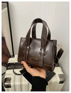 Close-up of a glossy dark brown leather handbag with gold-tone hardware and top handles