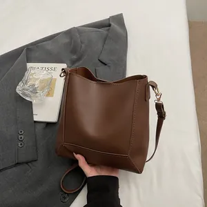 Detailed view of dark brown leather bucket bag with premium stitching and adjustable strap
