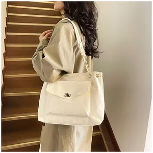 Gros plan d'un sac cabas en cuir synthétique crème avec bandoulière chaîne sur modèle