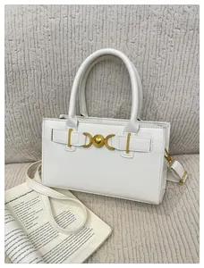 Detail of white leather handbag featuring gold heart-shaped hardware and a round handle