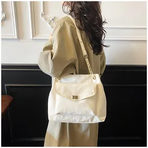 Détail du sac à bandoulière beige avec texture délicate et fermoir tournant en métal doré