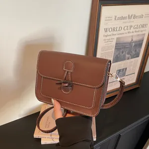 Detail view of vintage brown crossbody bag with contrast stitching and unique toggle closure