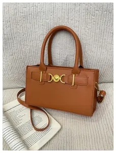Detail of caramel brown leather handbag with golden heart lock on white textured background