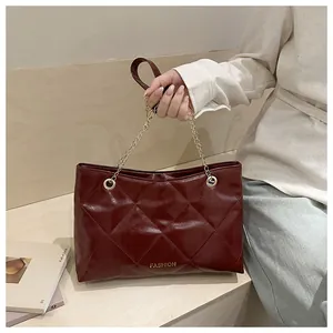 Détail d'un sac cabas bordeaux matelassé avec anse en chaîne dorée et inscription Fashion