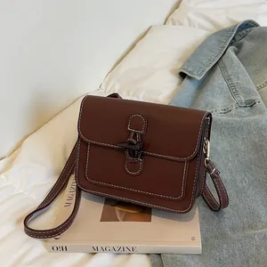 Detailed view of dark brown vintage square bag with contrast stitching and horn buckle