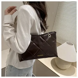 Sac bandoulière matelassé marron foncé avec chaîne dorée porté par un mannequin