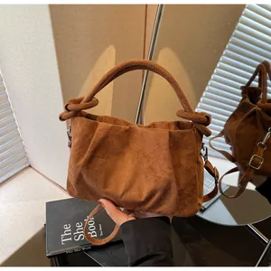 Detailed close-up of brown suede small square bag with decorative knot handle