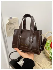 Detail of a vintage dark brown oil-wax leather handbag with gold metal hardware and strap