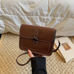 Detail of vintage brown leather crossbody bag with toggle closure and white stitching