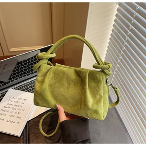 Detail of green faux suede handbag featuring unique knot handle and textured folds