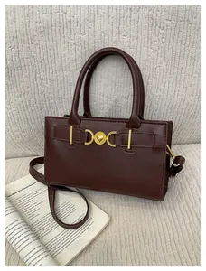 Detail of elegant dark brown leather handbag with gold heart buckle and crossbody strap