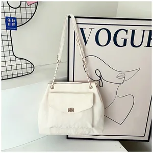Détail macro du sac en cuir plissé blanc avec fermoir doré tournant et bandoulière en chaîne