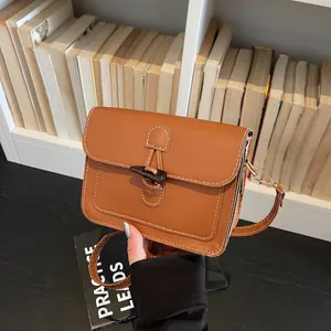 Detail of vintage brown square bag featuring white contrast stitching and a toggle closure