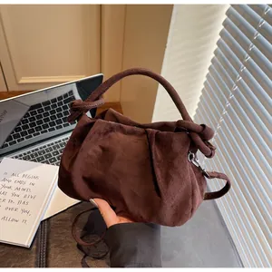 Detail of dark coffee suede handbag featuring elegant pleated texture and knotted handle
