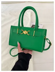 Close-up of green handbag featuring golden heart emblem and textured PU leather finish