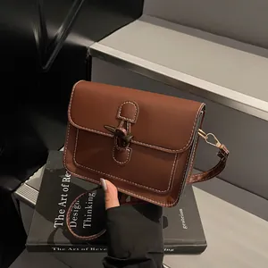 Brown retro shoulder bag detail featuring contrast stitching and a unique horn buckle closure