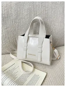 Detail of white leather handbag with golden lettering and detachable shoulder strap buckle