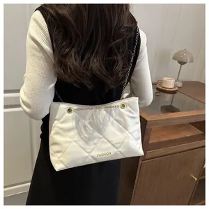 Détail d'un sac cabas matelassé blanc avec chaîne dorée porté par un mannequin
