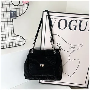 Détail d'un sac cabas noir plissé avec fermoir doré et bandoulière en chaîne élégante