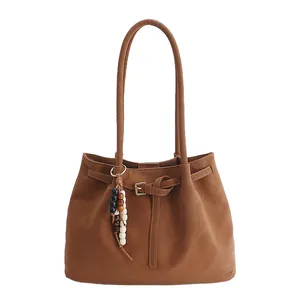 Borsa tote in pelle marrone con spalline sottili e ciondolo di perline alla moda su bianco
