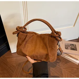 Macro detail of brown faux suede handbag showing knotted handle and vintage texture